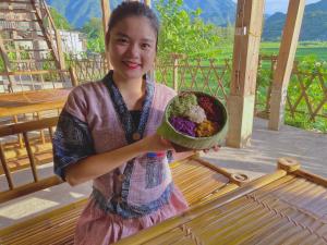 Meadow Mai Chau Homestay في ماي تشاو: فتاة صغيرة تحمل وعاء من الطعام