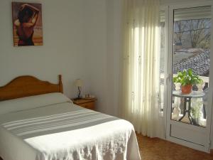 1 dormitorio con 1 cama y puerta corredera de cristal en Hostal D´Ernes, en Alcalá del Júcar