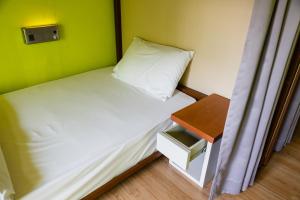 Dormitorio pequeño con cama y mesa en Siamaze Hostel, en Bangkok