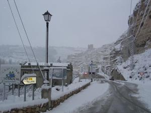 een straat bedekt met sneeuw met een straatlicht en gebouwen bij Hostal D´Ernes in Alcalá del Júcar