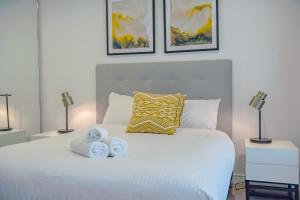 AirTrip Apartments on Tribune Street في بريزبين: غرفة نوم بسرير ابيض عليها منشفتين