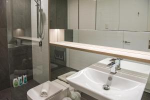 een badkamer met een wastafel, een toilet en een spiegel bij AirTrip Apartments on Tribune Street in Brisbane