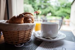 een broodmand en een kopje koffie op een tafel bij Hotel Le Branhoc - Brit Hotel Auray in Auray