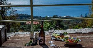 uma mesa com uma garrafa de vinho e uma taça de comida em Ξενώνας Αρσινόη- ΜΕΘΑΝΑ ΜΕΓΑΛΟΧΩΡΙ em Methana