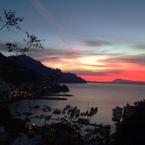 una puesta de sol sobre un cuerpo de agua con una ciudad en Amalfi Resort, en Amalfi
