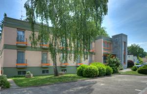 ein Apartmenthaus mit einem Baum davor in der Unterkunft Hotel Ascona in Bad Krozingen