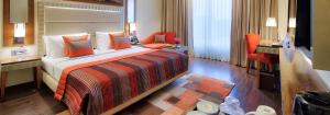 a hotel room with a large bed and a chair at Ramada Gurgaon Central in Gurgaon