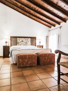 a bedroom with a bed with two ottomans at Hotel rural Entreviñas in Caudete de las Fuentes