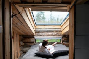 a woman sitting on a bed in a tiny house at Veskaranta Sky View Villas in Ruka