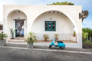 a woman sitting on a bench in front of a house at Hotel Ravesi in Malfa