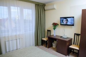 a hotel room with a desk and a tv and a window at Guest House Topaz in Adler