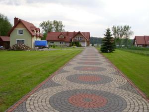 a cobblestone driveway in a yard with houses at Agroturystyka Düsselkamp Tumiany in Barczewo