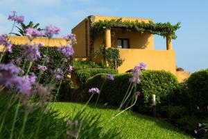 a house with purple flowers in front of a yard at Hotel Ravesi in Malfa