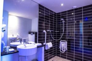 a black tiled bathroom with a sink and a shower at Holiday Inn Express Dijon, an IHG Hotel in Dijon