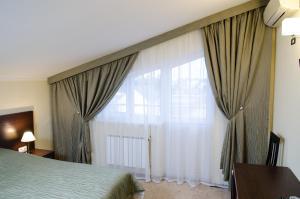 a bedroom with a bed and a large window at Guest House Topaz in Adler