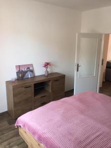 a bedroom with a pink bed and a wooden dresser at Apartmán Melody in Ústí nad Labem