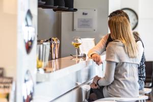 une femme assise dans un bar avec un verre de vin dans l'établissement Holiday Inn Express Dijon, an IHG Hotel, à Dijon