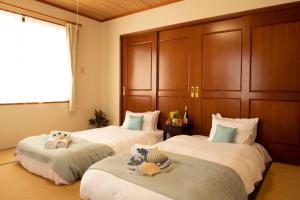 ein Schlafzimmer mit zwei Betten mit ausgestopften Tieren in der Unterkunft Miyakojima White House in Miyako-jima