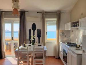 a kitchen with a table with chairs and a view of the ocean at Appartamenti Sole 1 in Alghero