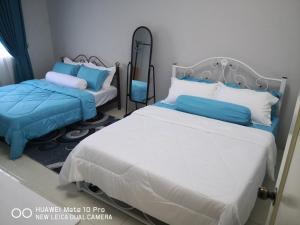 1 Schlafzimmer mit 2 Betten mit blauen und weißen Kissen in der Unterkunft Zumara Homestay Jerantut Pahang in Jerantut