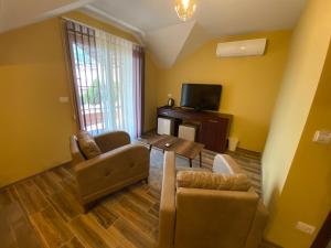 een woonkamer met een tafel en stoelen en een televisie bij Hotel Kolonja's in Debar