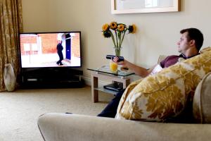 a man sitting on a couch playing a video game at Silversprings - City Centre Apartments with Parking in Exeter