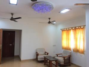 uma sala de estar com 2 cadeiras, uma mesa e um lustre em Swarna Sudarshan Service Apartment @ Adyar chennai em Chennai