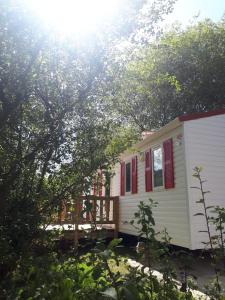 Casa blanca pequeña con ventanas rojas y porche en Camping Playa Sauces en Ribadesella