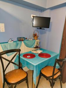 mesa azul con 2 sillas y TV en Mama's Cozy Room 1 en Kalambaka