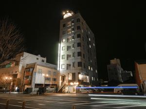 een hoog gebouw met 's nachts een klokkentoren bij Hotel AreaOne Nobeoka in Nobeoka