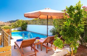 a patio with a table with an umbrella and a pool at Kolymbia Village in Kolymbia