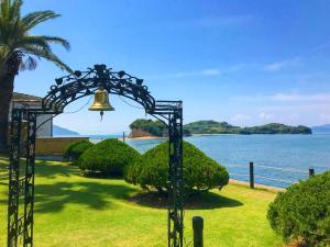 a bell in the grass next to a body of water at Shodoshima International Hotel in Tonosho