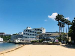 a beach with palm trees and a large building at Shodoshima International Hotel in Tonosho