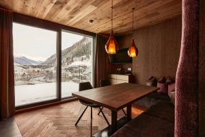a dining room with a table and a large window at Hotel Alpina in Ischgl