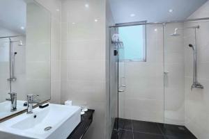 un bagno bianco con lavandino e doccia di Aston Inn Gideon Batam a Nagoya Altre 27 foto