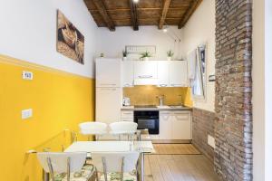 a kitchen with white tables and chairs and a brick wall at Nel cuore di Ferrara in Ferrara