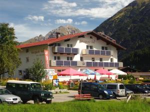 un gran edificio con coches estacionados frente a él en Holzgauerhof, en Holzgau