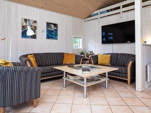 ein Wohnzimmer mit Sofas, einem Tisch und einem TV in der Unterkunft 6 person holiday home in Pr st in Præstø