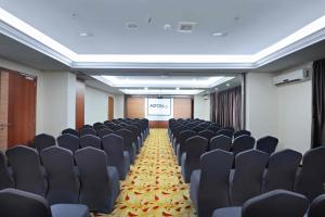 a conference room with black chairs and a screen at ASTON Inn Gideon Batam in Nagoya