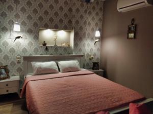 Schlafzimmer mit einem Bett mit rosa Tagesdecke in der Unterkunft Mama's Cozy Room 2 in Kalambaka