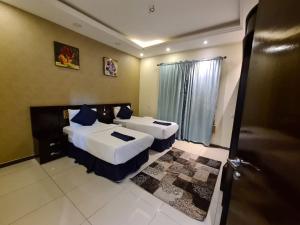a hotel room with two beds and a door at Rekaz Aparthotel in Makkah