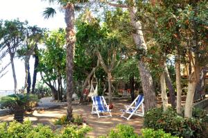 dos sillas azules sentadas a la sombra de los árboles en Le Mànnare Case Vacanze di Metopa srl, en Piano Conte
