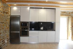 a kitchen with white cabinets and stainless steel appliances at Casa do Vale da Mula in Almeida