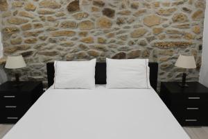 um quarto com uma cama branca e uma parede de pedra em Casa do Vale da Mula em Almeida