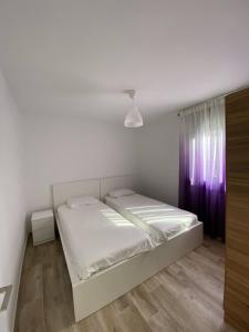 a white bedroom with a bed and a purple curtain at Josep Tarradellas Entire Apartment in Sabadell