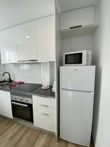 cocina blanca con nevera y microondas en Josep Tarradellas Entire Apartment, en Sabadell
