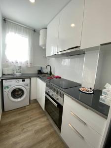 a kitchen with white cabinets and a washing machine at Josep Tarradellas Entire Apartment in Sabadell