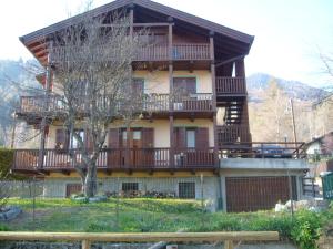 Una gran casa con balcones y un árbol en Chalet Madonna di Campiglio CIPAT ZERO22143-AT-ZERO69206, en Madonna di Campiglio