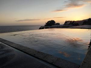 Água de Pau的住宿－羅德里格斯度假屋，日落时分在海边的游泳池