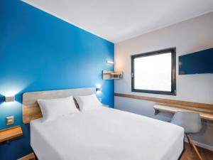 um quarto com uma cama branca e uma parede azul em ibis budget Santiago Providencia em Santiago